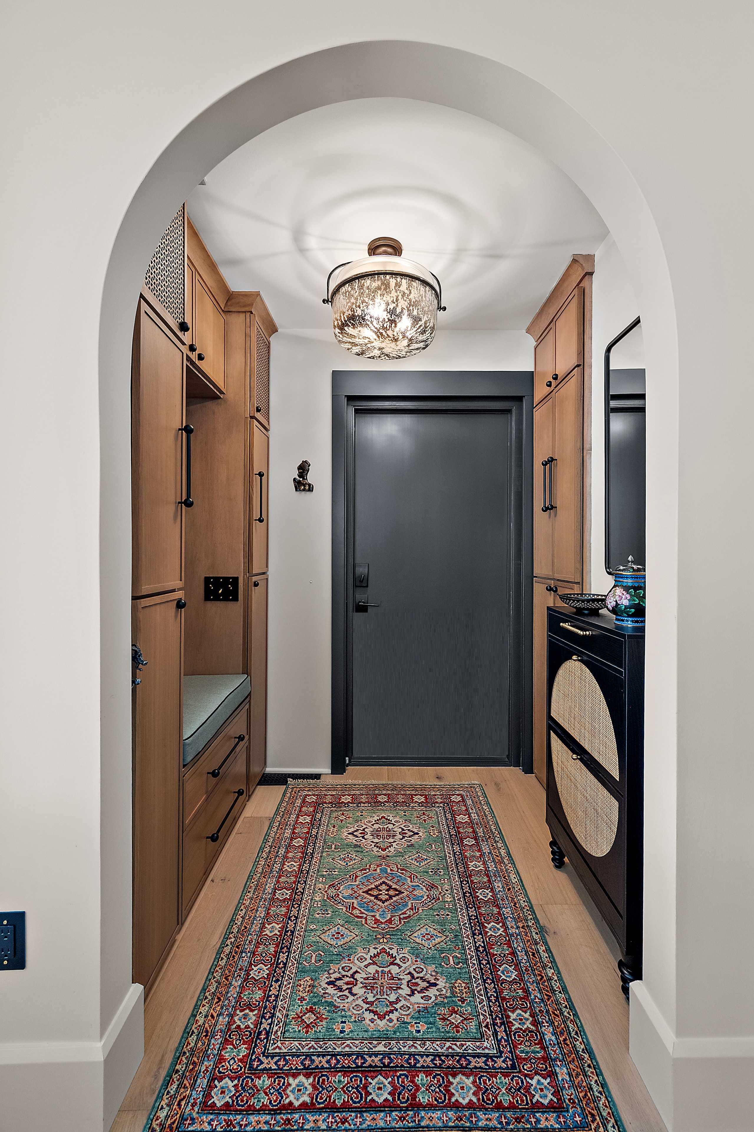 Arched hallway with wood cabinetry and black door